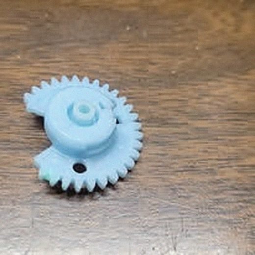 Close-up of a small blue precision gear from a mechanism repair